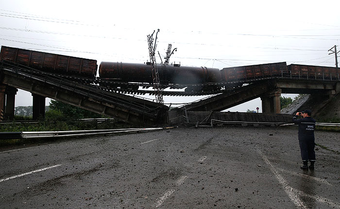 Сотрудник МЧС Украины фотографирует место происшествия в районе населенного пункта Новобахмутовка Донецкой области Украины, где был взорван железнодорожный мост над дорогой, ведущей из Славянска в Мариуполь.