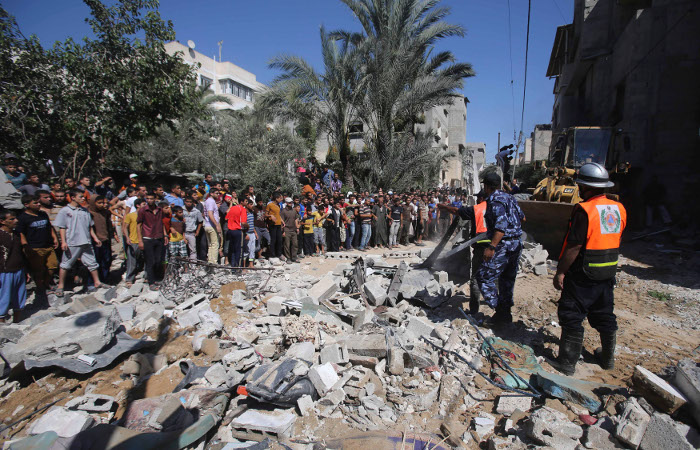 Палестинцы смотрят на дом, разрушенный авиаударом.
