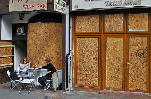 Посетители винного бара в западной части Лондона. Множество магазинов, баров и прочих подобных заведений теперь защищают свои витрины специальными щитами