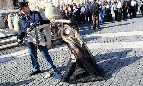 Как сообщается на сайте движения FEMEN, две участницы акции были задержаны еще на подходе к площади. Лидер движения Александра Шевченко пробралась в центр государства Ватикан на площадь святого Петра и устроила топлесс-акцию под балконом Папы Римского Бенедикта XVI.