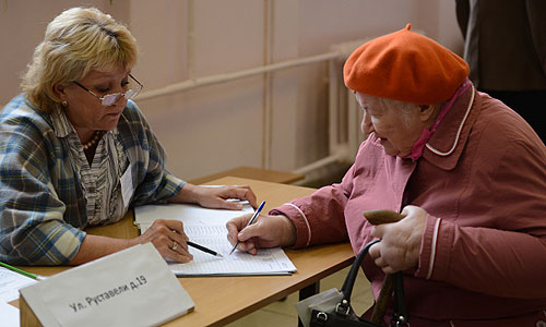 Женщина получает избирательный бюллетень на одном из избирательных участков на выборах мэра Москвы.