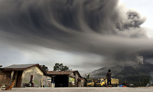 Жительница Индонезии наблюдает за извержением пепла в районе, где находится вулкан Синабунг.
