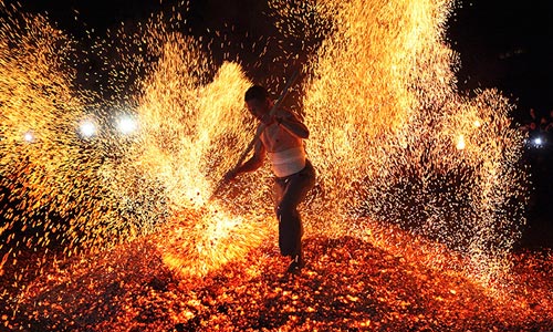Мужчина поднимает снопы искр во время традиционного "хождения по огню" в китайской провинции Чжэцзян.
