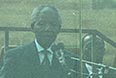 Нельсон Мандела произносит инаугурационную речь из-за пуленепробиваемого стекла.