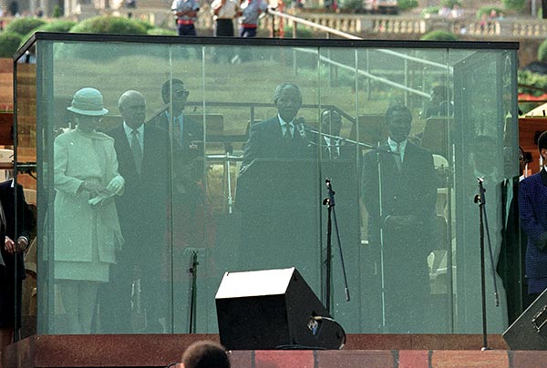 Нельсон Мандела произносит инаугурационную речь из-за пуленепробиваемого стекла.