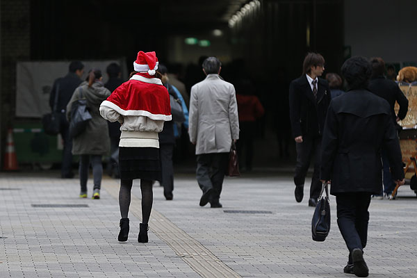 Девушка в накидке и шапке Санта Клауса на одной из улиц Токио.