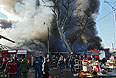 Сотрудники "Службы спасения" и прохожие во время пожара на центральном рынке "Беркат" в Грозном.