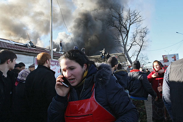 Продавщица говорит по телефону во время пожара на центральном рынке "Беркат" в Грозном.