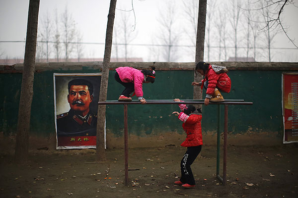 Школьницы играют на площадке на фоне портрета Иосифа Сталина в одной из китайских провинций.