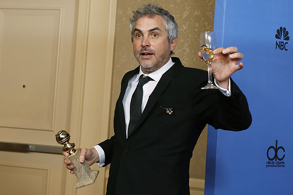 Альфонсо Куарон с бокалом шампанского и "глобусом" лучшему режиссеру, полученным за фильм "Гравитация".