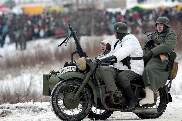 Участники военно-исторической реконструкции едут на мотоцикле.
