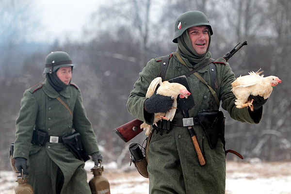 Участник военно-исторической реконструкции "В полосе прорыва" несет двух куриц.
