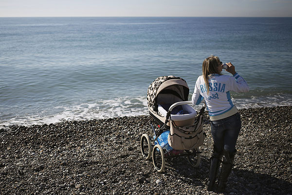 Женщина с коляской и прохладительным напитком на берегу Черного моря.
