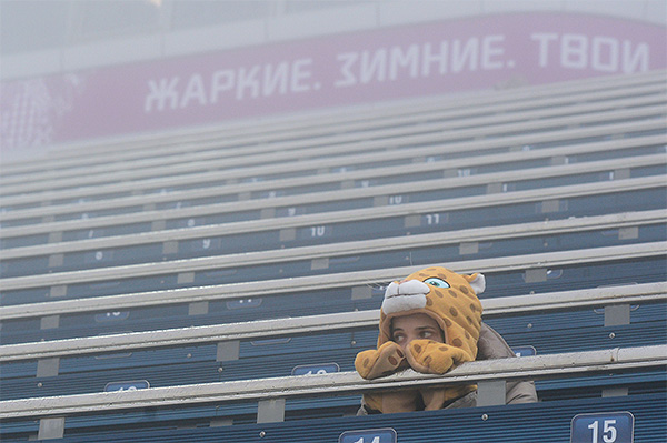 Болельщица грустит на трибуне перед началом гонки с масс-старта в соревнованиях по биатлону среди мужчин на XXII зимних Олимпийских играх в Сочи.