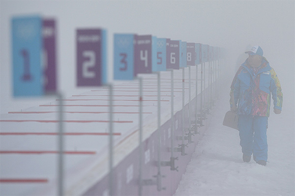 Сотрудник лыжно-биатлонного комплекса "Лаура" перед началом гонки с масс-старта в соревнованиях по биатлону среди мужчин на XXII зимних Олимпийских играх в Сочи.