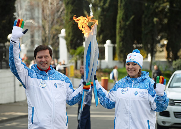 Старший вице-президент оргкомитета "Сочи-2014" Денис Секачев и факелоносец Александра Ступко во время эстафеты паралимпийского огня в Сочи.