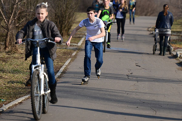 Подростки катаются на велосипедах и роликовых коньках в парке "Кузьминки-Люблино".