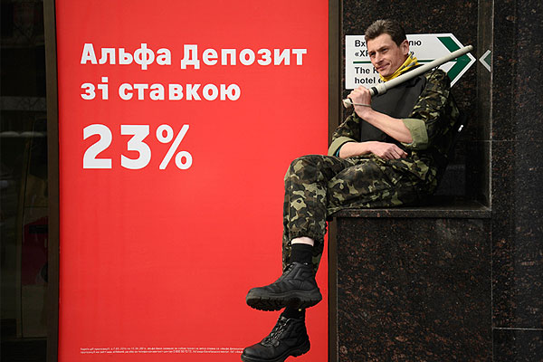 Участник "самообороны Майдана" сидит перед киевским офисом Альфа-банка.