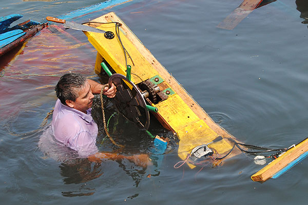 Рыбак пытается спасти свою лодку, смытую цунами в портовом городе Икике.