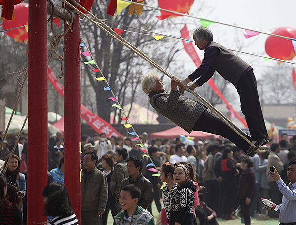 Пожилые женщины катаются на качелях в Китае.