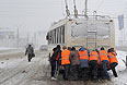 Работники коммунальных служб толкают троллейбус во время сильного снегопада в Челябинске.