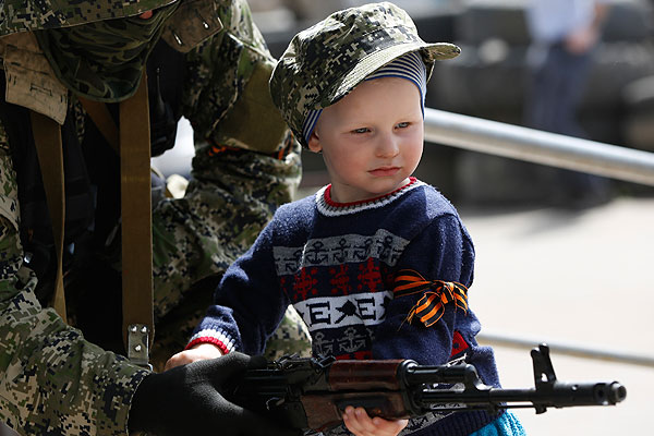 Вооруженный мужчина по просьбе отца ребенка позирует с ним для фотографий возле здания администрации города.