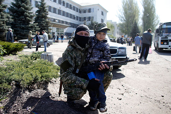 Вооруженный мужчина в балаклаве позирует с ребенком возле администрации города.