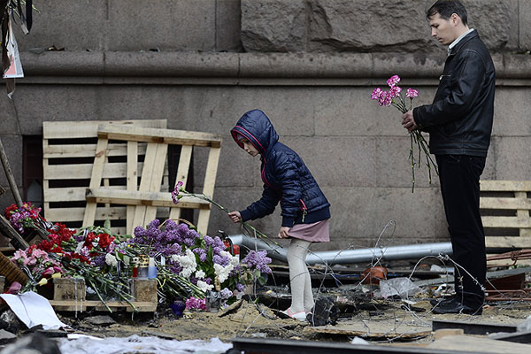 Мужчина с девочкой возлагают цветы в память о погибших в результате пожара в Доме профсоюзов на площади Куликово Поле в Одессе.