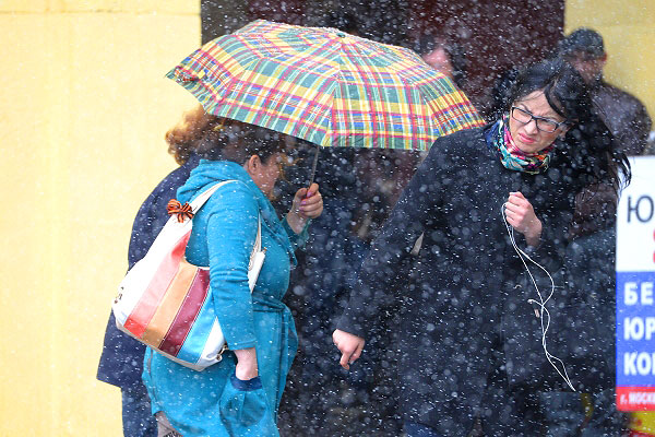 Жители города укрываются от мокрого майского снега.