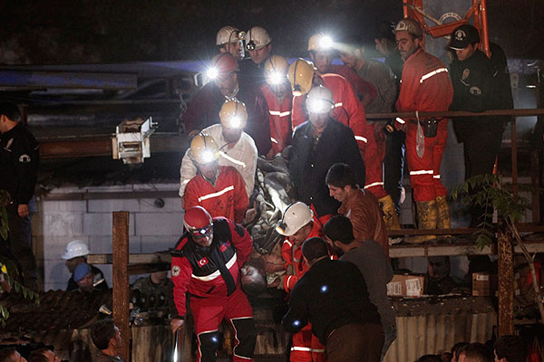 Группа турецких спасателей выносит на носилках пострадавшего от взрыва шахтера.