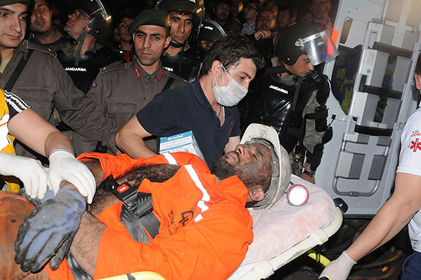 Пострадавшего шахтера подвозят к машине скорой помощи.