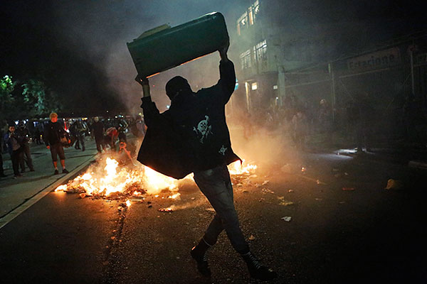 Участник протестов готовится швырнуть урну.