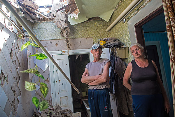 Жители Славянска в своем разрушенном в результате ночного артобстрела доме.