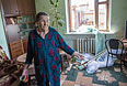 Пожилая женщина в своем доме, пострадавшем в результате ночного артобстрела.