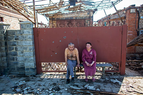 Жители Славянска сидят у ворот своего дома, пострадавшего в результате ночного артобстрела.