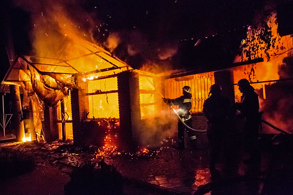 Пожарные тушат здание, загоревшееся после попадания снаряда во время артобстрела украинскими военными позиций народного ополчения Славянска.