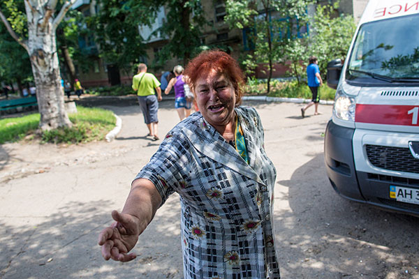 Жительница Славянска во дворе дома после попадания туда снаряда.