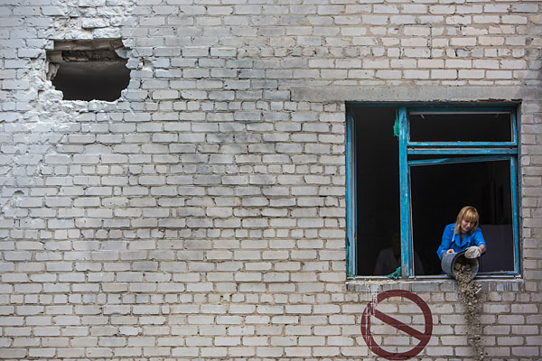 Работники больницы убирают последствия разрушений от попадания снаряда в здание больницы в Славянске во время обстрела украинскими силовиками жилых районов города.