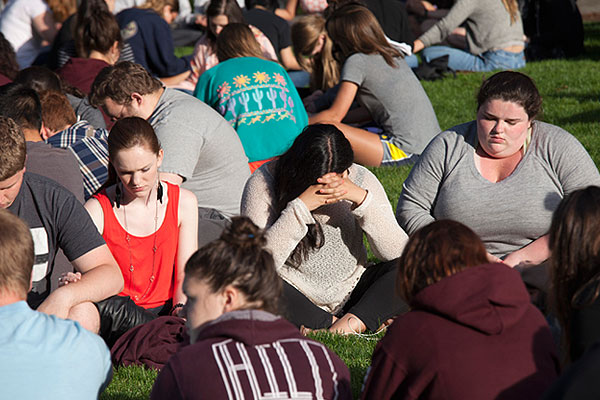 Студенты молятся на лужайке кампуса.