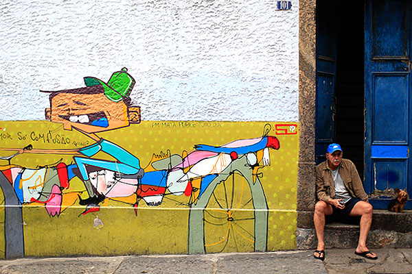 Мужчина с плеером и йоркширским терьером сидит рядом с граффити в районе Санта Тереса в Рио-де-Жанейро. Фотография - часть проекта "На обочине", обобщающего видение ЧМ-2014 зарубежными фотографами.