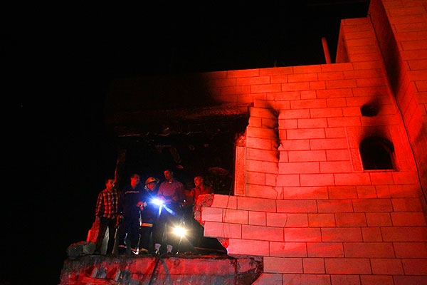 Пожарные и местные жители осматривают развалины одного из домов предполагаемых похитителей израильских детей.