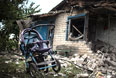 Детская коляска во дворе разрушенного дома.