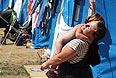 Женщина переодевает ребенка на территории севастопольского лагеря для беженцев.