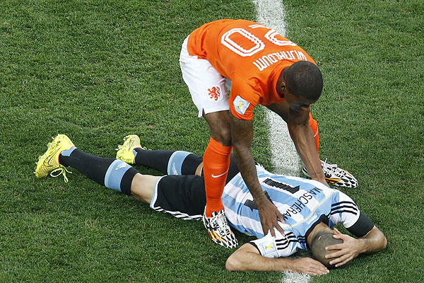 Голландский игрок Вейналдум склонился над травмированным аргентинцем Маскерано.