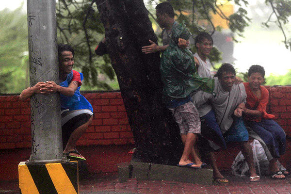 Жители Манилы держатся за столбы и деревья.