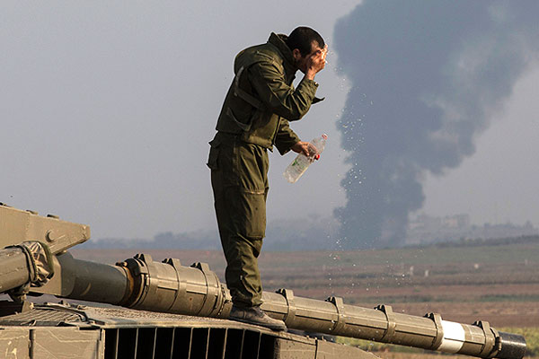 Израильский солдат умывается на танке.