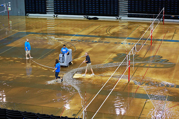 Рабочие пытаются собрать воду в спортзале.