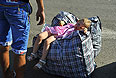 Девочка отдыхает на сумках с вещами в ожидании проезда через границу.
