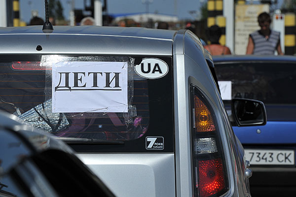 Очередь на пропускном пункте. На многих машинах закреплены такие предупреждения.