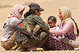 Женщина из отряда помощи курдам утешает женщин с маленьким ребенком.